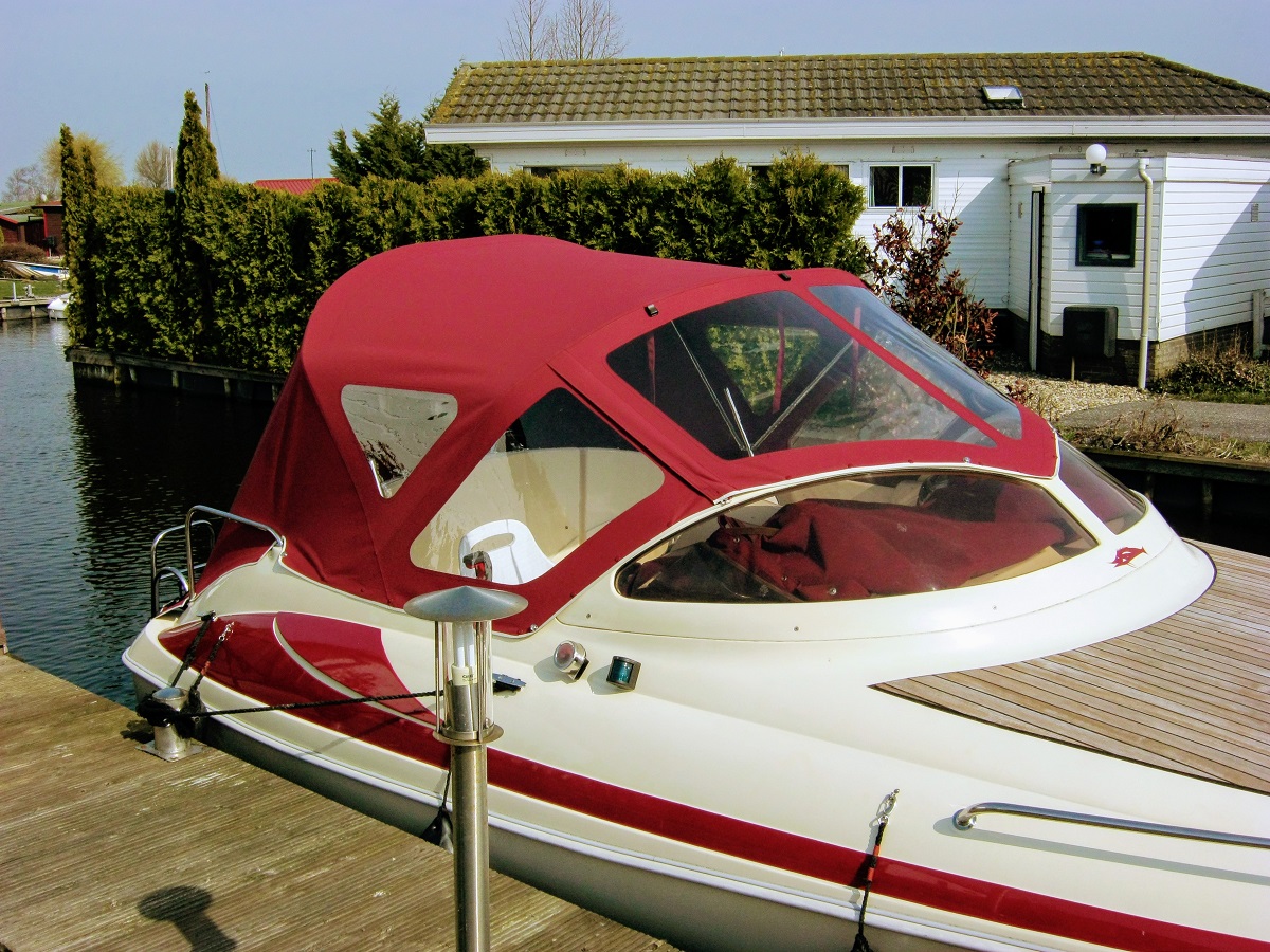 Rotes Cabriozelt auf weißem Boot im Wasser