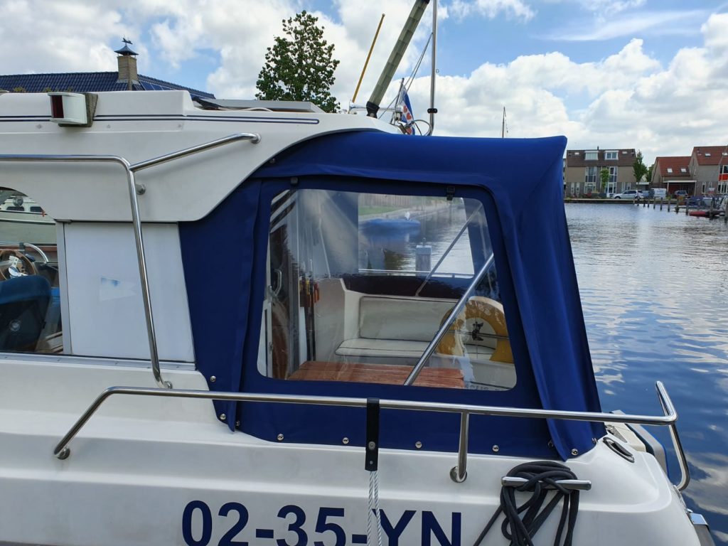 Blauwe achtertent op witte boot in water