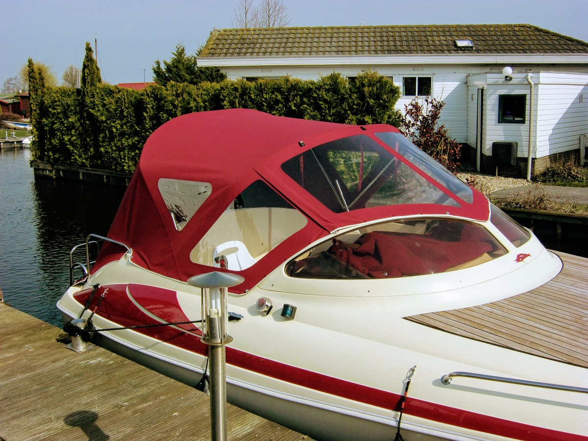 Red convertible tent on white boat in water