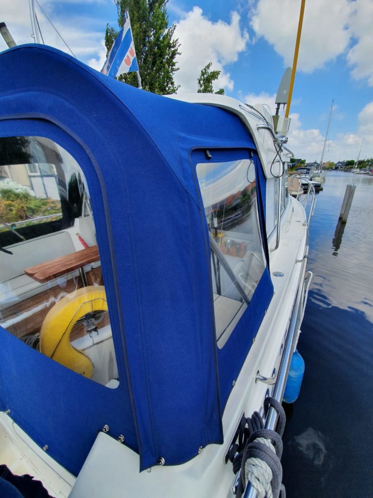 Blue rear tent open on white boat in harbor
